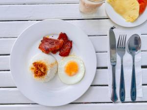 a white plate with eggs and bacon on a table at Mariner's Pension House in Puerto Princesa City