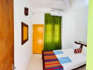恩比利皮蒂耶Vishmee Holiday Inn的一间设有床铺和绿帘的房间 更多46张照片