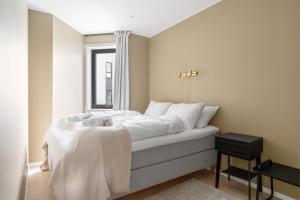 a bedroom with a bed with white sheets and a window at Premium Penthouse in Tromsø - Northern lights, City, Sea & Mountain view in Hjorten