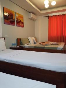 a bedroom with two beds and a red curtain at Aqua Travel Lodge in El Nido