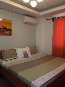 a bedroom with a large bed with a red curtain at Aqua Travel Lodge in El Nido