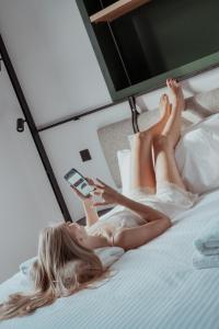 a woman laying on a bed while holding a cell phone at Kentrikon 1924 Boutique Hotel, Old Town in Paphos City