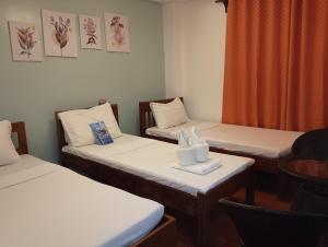 a room with three beds and an orange curtain at Aqua Travel Lodge in El Nido