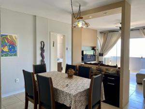 Un comedor y una sala de estar con mesa y sillas. en Apto Confortável p/ até 9P, 50mts do mar Piçarras, en Piçarras