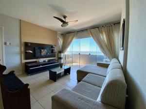 Una sala de estar con dos sofás y un televisor. en Apto Confortável p/ até 9P, 50mts do mar Piçarras, en Piçarras