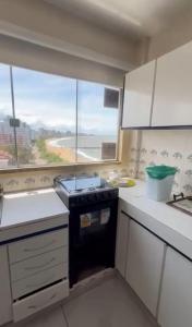 cocina con fogones y ventana grande en Apto Confortável p/ até 9P, 50mts do mar Piçarras, en Piçarras