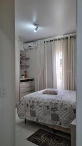 a white bedroom with a bed and a window at Casa para 7 Pessoas em Bombas 600 m da Praia in Bombinhas