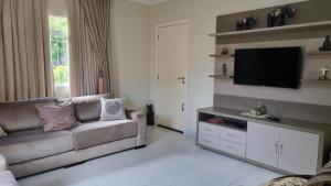 a living room with a couch and a flat screen tv at Casa para 7 Pessoas em Bombas 600 m da Praia in Bombinhas