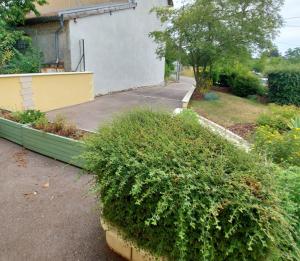 a house with a green bush next to a driveway at Chambre spacieuse climatisée - Petit déjeuner inclus in Euville
