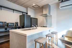 a kitchen with a sink and two bar stools at Restia Solace in Sapporo