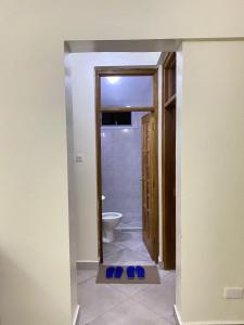 a bathroom with a toilet and a doorway with blue slippers at Zuri Homes 6 B in Mombasa +4 photos