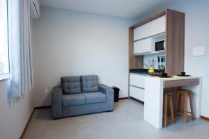 a living room with a blue chair and a kitchen at Studio Prático Próximo ao Aeroporto in Florianópolis