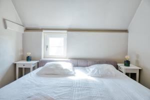 a bedroom with a white bed with two tables at Cozy apartment with stunning view over the fields in De Haan
