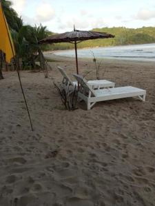 a bed and an umbrella on a beach at Akoya Beachpark and Cottages in El Nido