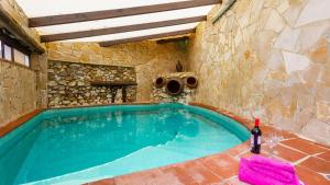 Una piscina en una casa de piedra con una botella de vino. en Heated pool villa - El Acebuchal, en Acebuchal