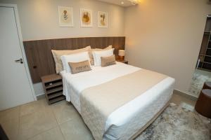 a bedroom with a large white bed with two pillows at Concept Hotel Flat in Balneário Camboriú