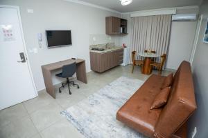 a living room with a brown leather couch and a kitchen at Concept Hotel Flat in Balneário Camboriú
