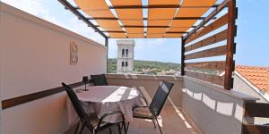 un balcón con mesa y sillas y una torre del reloj en Castello, en Mali Lošinj