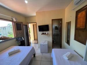 a room with two beds and a television in it at Pousada Sitio Preguicas in Barreirinhas