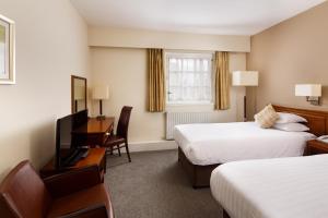 a hotel room with two beds and a desk at Mercure Perth Hotel in Perth