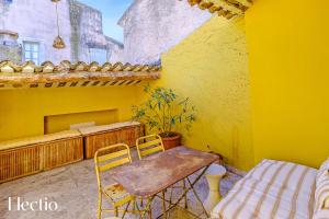 Maison de Caractère - Au cœur de Lourmarin في لورمارين: غرفة صفراء مع طاولة وكراسي على شرفة