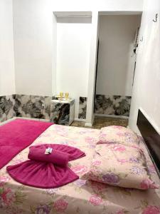 una camera da letto con letto e lenzuola e cuscini rosa di Quarto privado no centro 203 a Manaus
