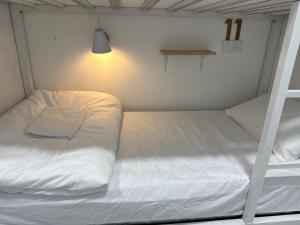 a white bed in a small room with a ladder at Putih Hostel in Klang
