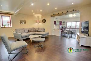 a living room with a couch and chairs and a kitchen at Maison de la vilaine in Saint-Dolay