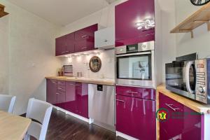 a kitchen with purple cabinets and a table and chairs at Maison de la vilaine in Saint-Dolay