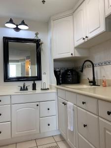 een keuken met witte kasten, een wastafel en een spiegel bij Beach Access Elegant Studio near Top Attractions in Ortona