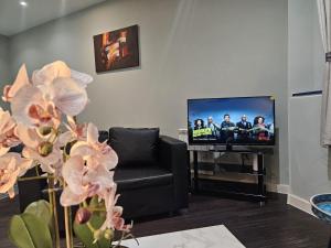 ein Wohnzimmer mit einem schwarzen Stuhl und einem TV in der Unterkunft The Skyline 2 - London Heathrow Stunning Private Studio Apartment - Family Friendly & Fully Equipped in Harmondsworth