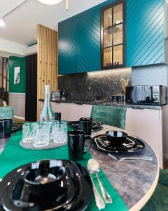 a kitchen with a table with black plates and utensils at Aparthotel Green Concrete - Free Beach Bus in Świnoujście