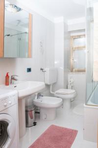 a white bathroom with a sink and a toilet at Cjase al Tistignar in Paluzza