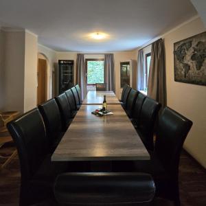 un lungo tavolo con sedie nere e un lungo tavolo con una bottiglia sopra di Ferienhaus Lemmerwald a Neerdar Altre 15 foto
