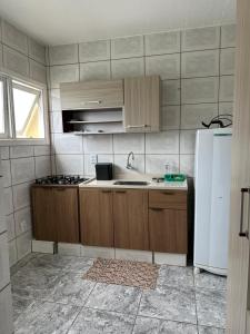 een keuken met houten kasten en een witte koelkast bij Hyago Monteiro in Capão da Canoa