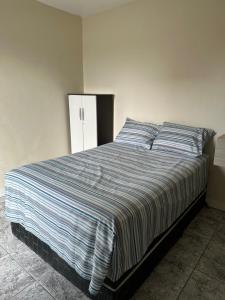 een slaapkamer met een bed met een blauw en wit gestreepte deken bij Hyago Monteiro in Capão da Canoa