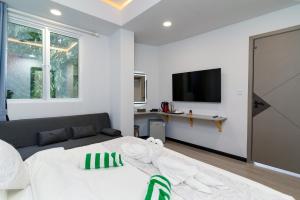 a white bedroom with a bed and a tv at Sunway Ukulhas in Ukulhas