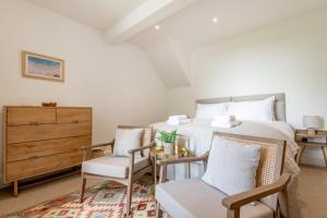 a bedroom with a bed and two chairs and a dresser at Caiplie Farmhouse, Caiplie, by Crail, KY10 3JR in Kilrenny