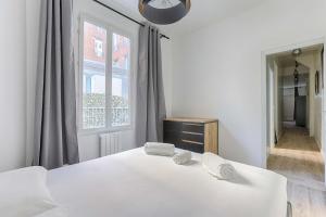 a white bedroom with a bed and a window at Appartement de charme à Boulogne in Boulogne-Billancourt