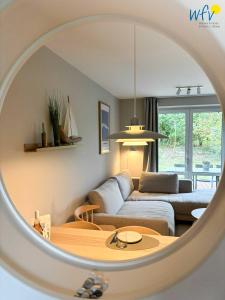 万根沃格Ferienhäuser Jadehörn Ferienhaus Dünen Hus的带沙发和镜子的客厅