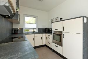 een keuken met witte kasten en een kookplaat oven bij Seegasse in Unter Göhren