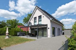 a white house with glass doors on a driveway at Ankerplatz 8 in Göhren-Lebbin