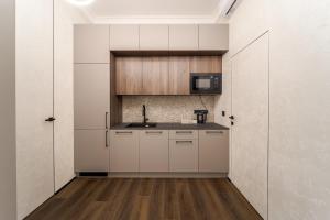 eine Küche mit weißen Schränken und einer Spüle und einer Mikrowelle in der Unterkunft Rynok Square Pidzemelya in Lwiw + 6 Fotos