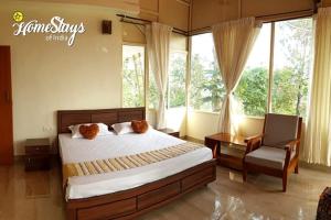 um quarto com uma cama, uma cadeira e janelas em KK Inn em Kanyakumari