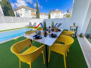 a table and chairs on a patio with a pool at Villa Allegra in Protaras