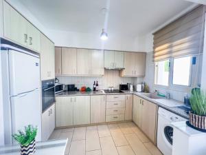 a kitchen with white cabinets and a washer and dryer at Villa Allegra in Protaras