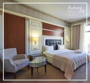 a bedroom with a bed and a chair and a table at Boulevard Side Hotel in Baku
