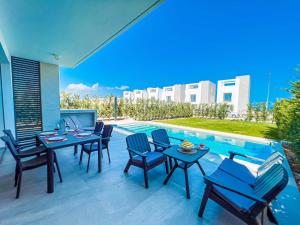 a patio with tables and chairs next to a swimming pool at Azure Villas by Marc in Paralimni