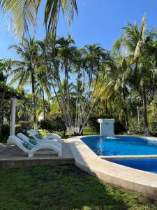 un gruppo di sedie sedute accanto a una piscina di Pool • Fire Pit • Game Room • Resort Access a Los Cóbanos