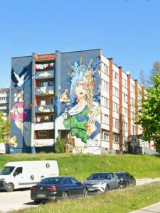 un murale sul lato di un edificio con auto parcheggiate di Airport & Station Stay Vilnius a VNO Altre 32 foto